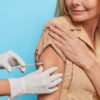 Unknown doctor makes insulin or flu vaccination shot to female patient holds syringe with dose of vaccine. Woman gets inoculation in shoulder protects herself against coronavirus. Health care