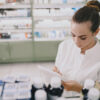 Medicine, pharmaceutics, health care and people concept. Female pharmacist taking medications from the shelf.